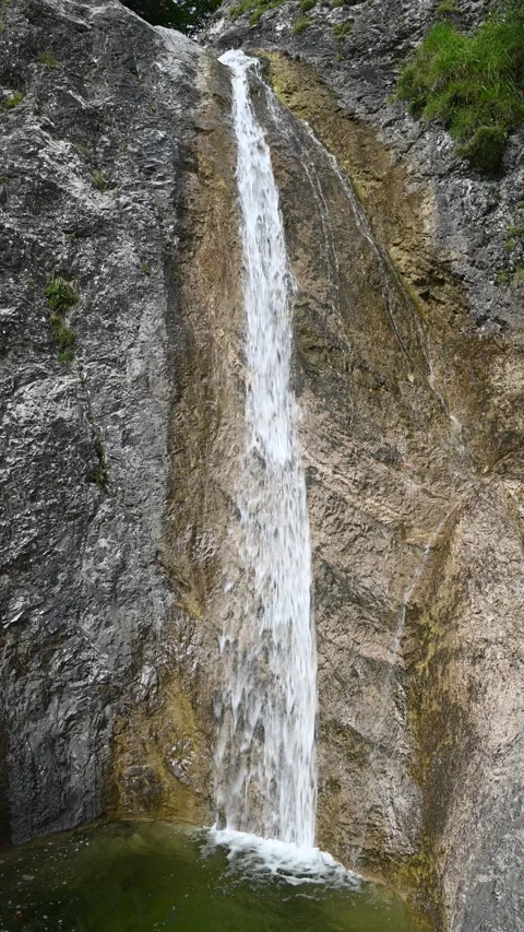 Vertical shot of a waterfall running over rocks into a pond Stock-Footage 260886222