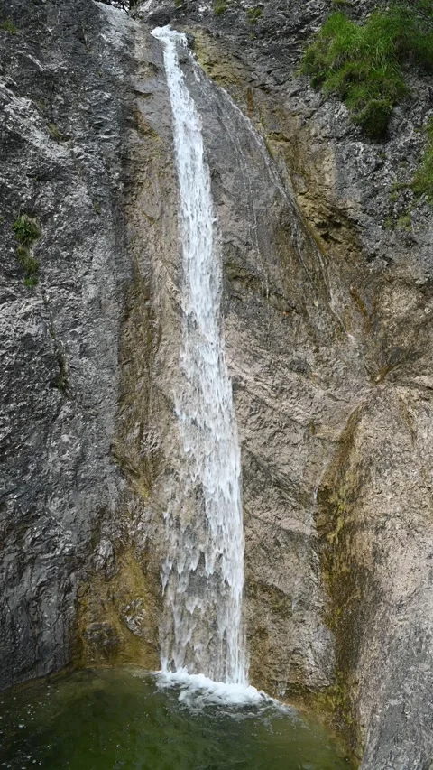 Vertical shot of a waterfall running over rocks into a pond Stock-Footage 260886884