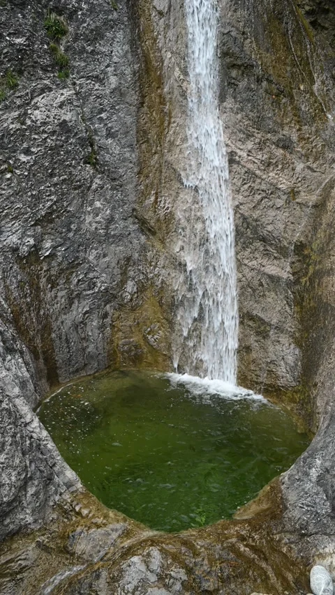 Vertical shot of a waterfall running over rocks into a pond, overcast Stock-Footage 260887417