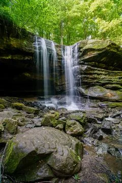 Vertical shot of a waterfall surrounded by cliffs and trees Stock Photos