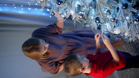 A vertical shot in which the son helps his mother decorate the Christmas tree. Stock Footage 259085573