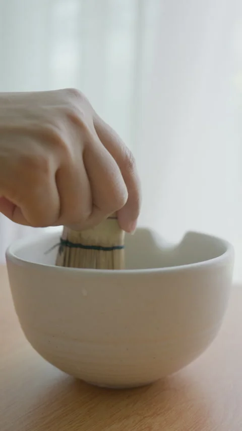Vertical shot whisking matcha green tea powder in a ceramic bowl Stock Footage 341169912