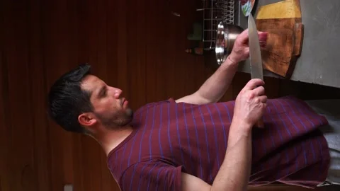 Vertical shot of a white man cutting steaks with a knife on a wooden board on a Stock Footage 199581145
