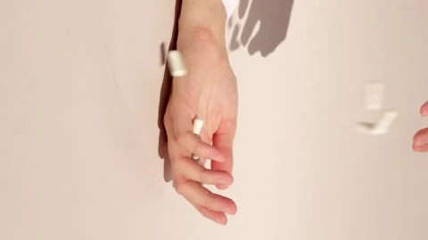 Vertical shot white pills drop on hand of unrecognized person beige background Stock Footage 229499458