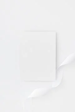 A vertical shot of a white rectangular paper and a ribbon isolated on white b Stock Photos