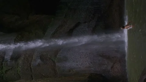 Vertical shot of wild waterfall in rocks, woman swimming and enjoying freshness Video stock 168861919