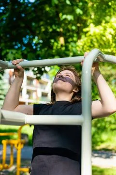 Vertical shot of woman doing pull ups on outdoor bar Fotos de archivo