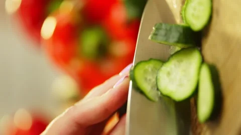 A vertical shot of women's hands cutting a green cucumber into circles. Stock Footage 296363318