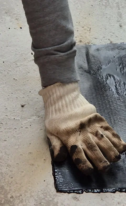 Vertical shot of worker heating bitumen membrane on flat roof 動画素材 345666044