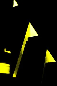 A vertical shot of the yellow lights of triangle shape on the wall in the dar Stockfoto's