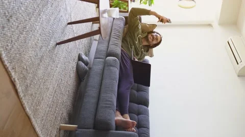 Vertical shot of young man on the sofa taking selfie while using laptop Stock Footage 164905784