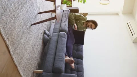 Vertical shot of young man using laptop on the sofa Stock Footage 164905259