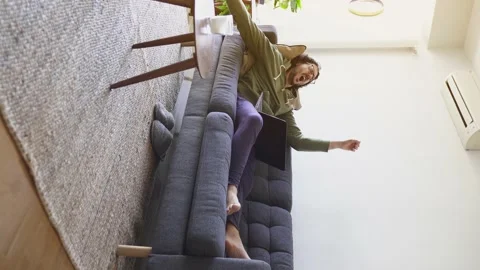 Vertical shot of young man waking up after nap with laptop on the sofa Stock Footage 164905984