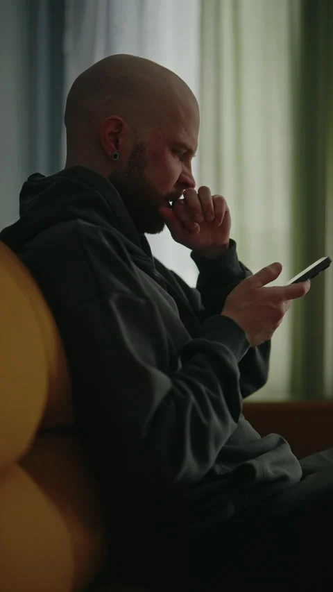 Vertical side view shot of exhausted bald man yawning reading news on smartphone Stock Footage 305514463