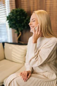 Vertical side view shot of joyful young woman talking on mobile phone sitting Stock Photos
