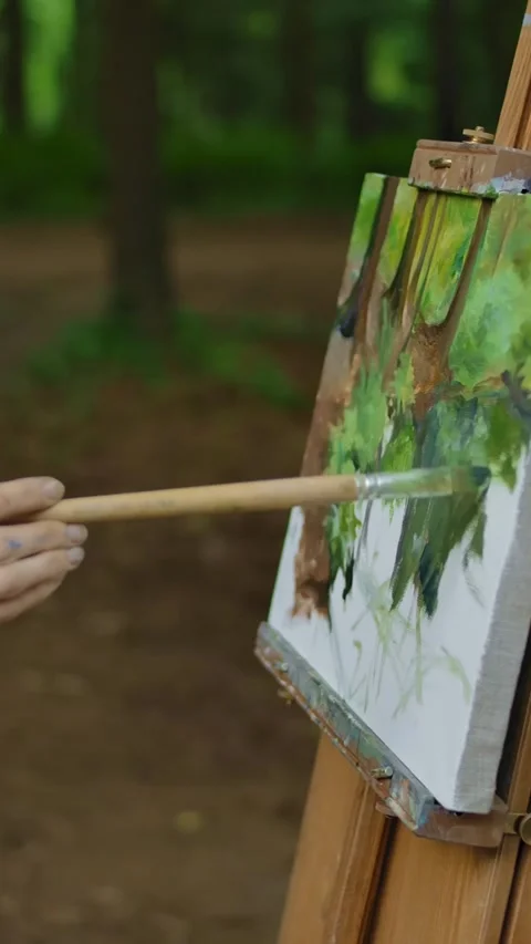 Vertical of Side view of a woman's hand painting a landscape on canvas in a park Stock Footage 276928266