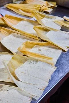 Vertical of silver tray of several pre-baked tamales with masa and corn husk Stockfoto's