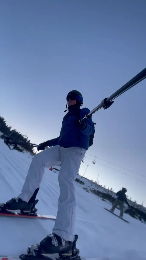 Vertical skier resting on snowy slope under clear blue winter sky Stock Footage 325647641