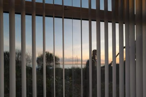 Vertical slat blinds on a window seen from the inside whilst a window cleaner Stock Photos