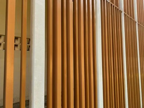 Vertical slats in warm tones frame a minimalist architectural wall Stock Photos