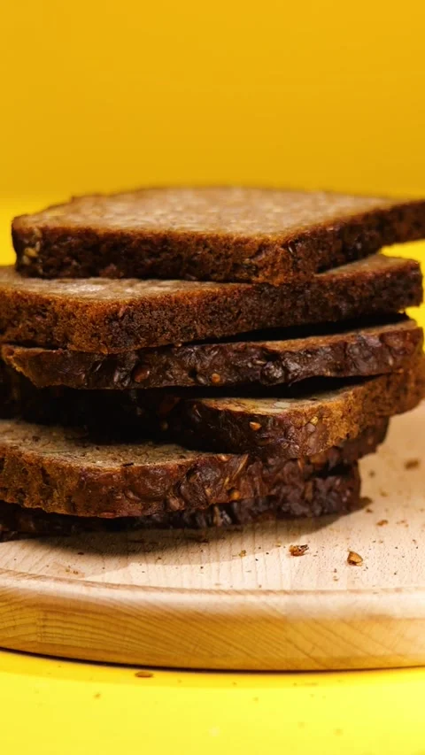 Vertical Slices of Fresh Dark Rye Bread Falling and Stacking on Yellow Backgroun 動画素材 292561727