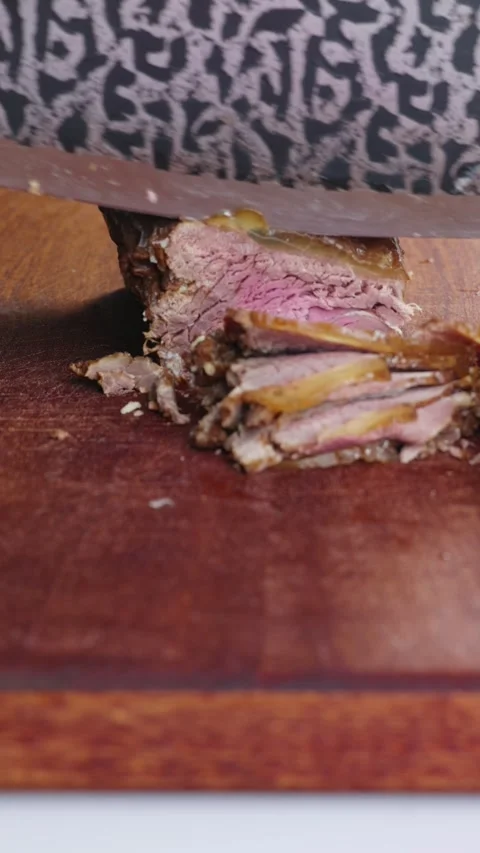 Vertical: Slicing braised beef into thin pieces with a knife. 库存影片 346502312