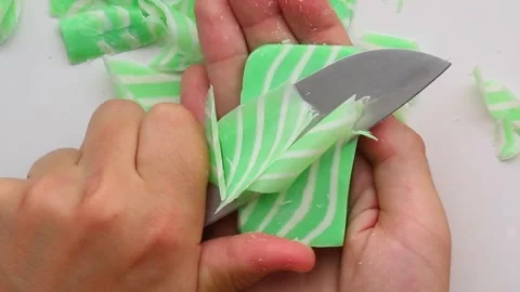 Vertical slicing of green soap bar creating soft ASMR curls Video stock 315418212