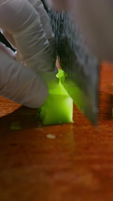 Vertical: Slicing peeled crisp green lettuce stem into thin pieces. Stock Footage 341837400
