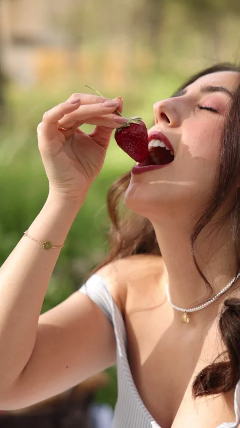 Vertical Slow Motion of Beautiful Young Woman Eating a Strawberry at Picnic Stock Footage 288855817