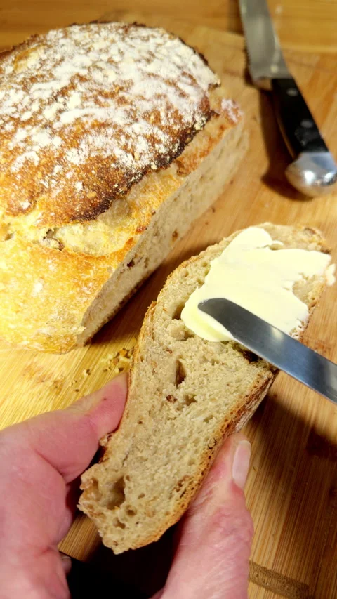 Vertical - Slow motion of butter being spread on a bread slice next to a loaf. Vídeos de archivo 303916268