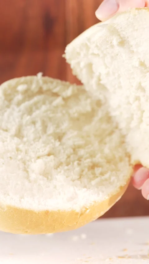 Vertical slow motion close-up of female hands separating a sliced soft bun .. Stock Footage 312169140