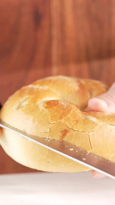 Vertical slow motion close-up of knife cutting soft bun in half on wooden b.. Stock Footage 312169003