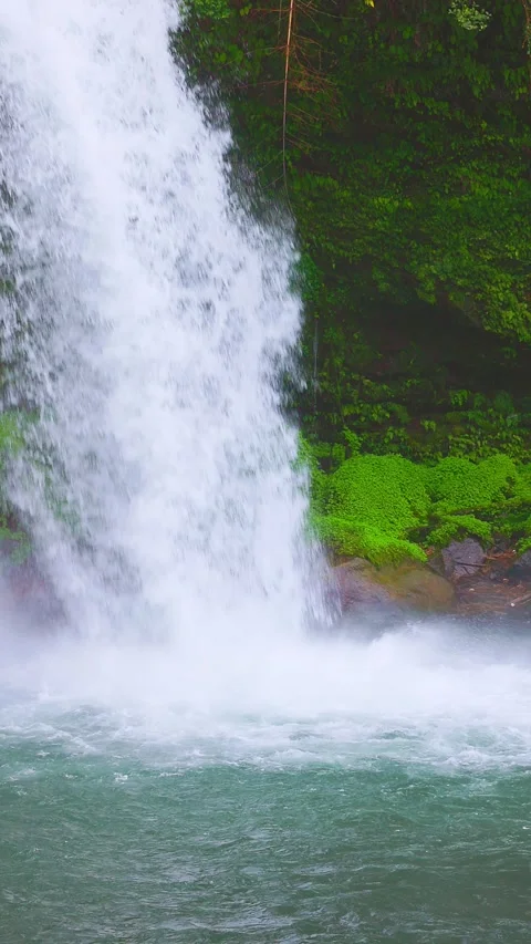 Vertical slow motion close up of waterfall crashing into clear pool 動画素材 341806420