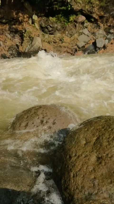 Vertical Slow motion of a fast flowing mountain river passing over rock Video stock 319921729