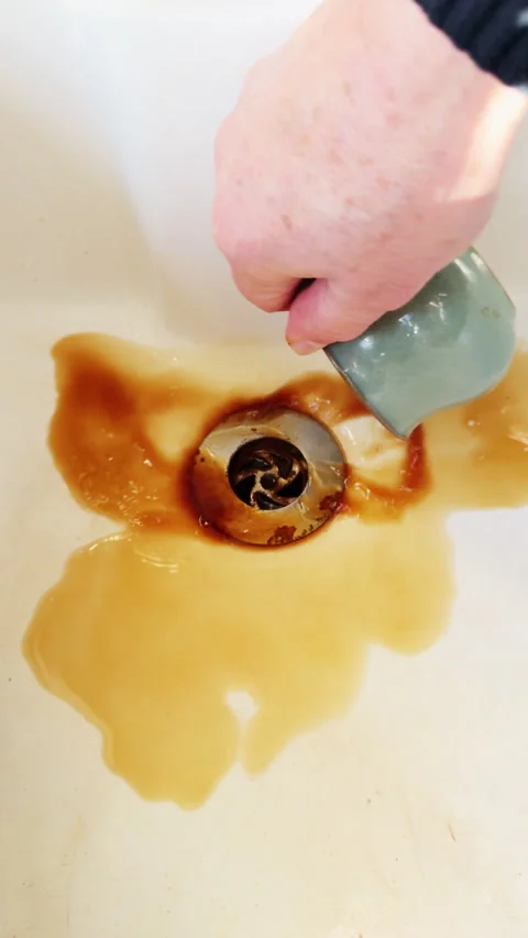 Vertical - Slow motion hand pouring a cup of black coffee down a sink plug hole. Video stock 297189686