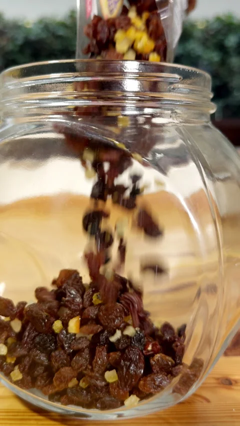 Vertical - Slow motion of mixed dried fruit pouring into a glass storage jar. Vídeos de archivo 295861111