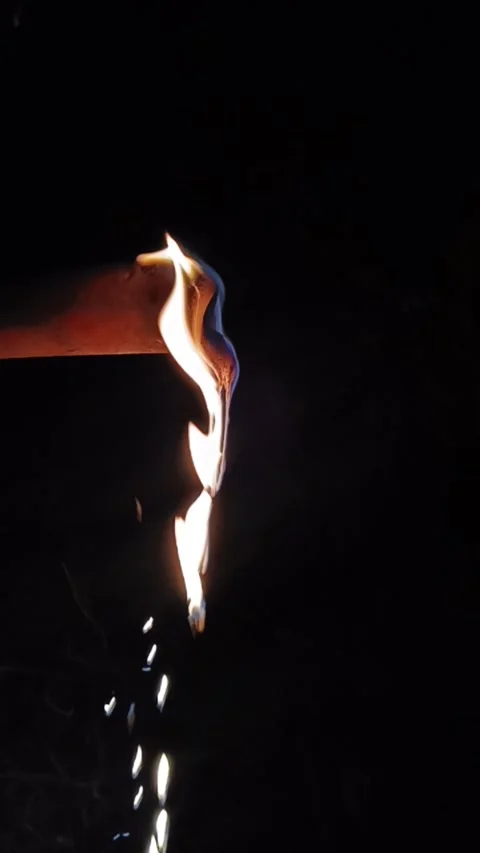 Vertical slow motion of molten flaming liquid dripping against an isolated b Stock-Footage 340265264
