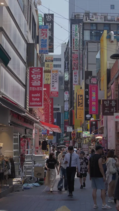 Vertical slow motion of pedestrians in busy Myeongdong shopping street Stock Footage 315465291