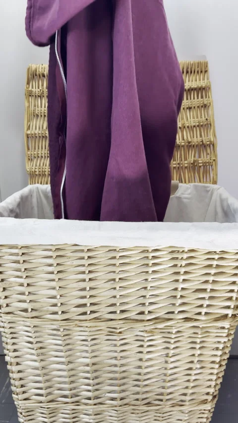 Vertical - Slow motion of a pink garment being dropped into a laundry basket. Video stock 300996201
