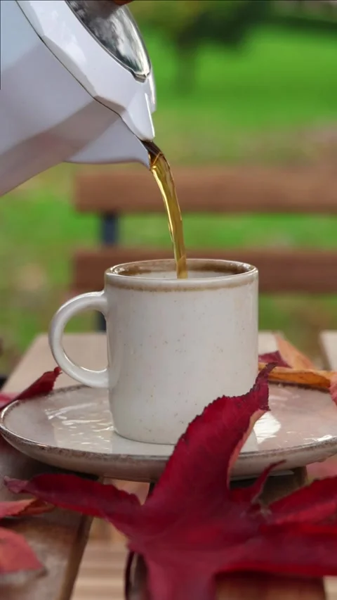 Vertical Slow motion pouring of tea into cup with autumn leaves Stock Footage 294187129