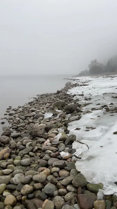 Vertical Slow Motion POV Walking on Icy Rocky Lake Shore in Morning Fog Stock Footage 328473785