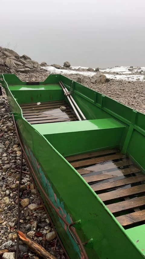 Vertical Slow Motion of Raindrops Falling into Green Boat on Rocky Shore Video stock 328473669