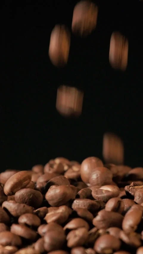 Vertical slow motion of roasted coffee beans falling. Stock Footage 233947856