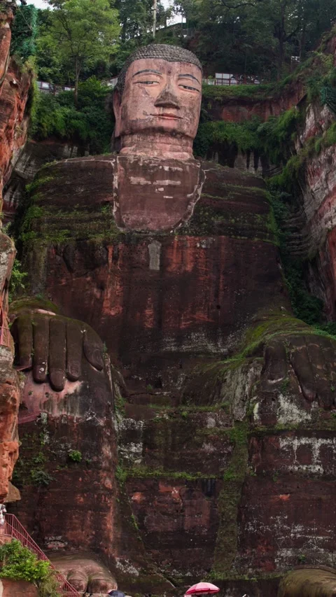 Vertical slow motion shot of Leshan Buddha carved into cliff Stock Footage 315682051