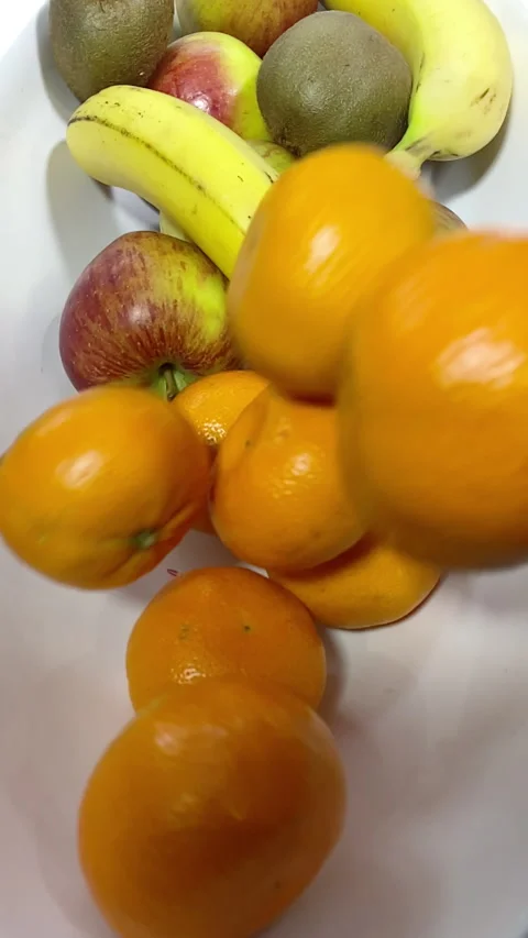 Vertical - Slow motion shot of mandarin oranges being tipped into a fruit bowl. Stock Footage 290117408