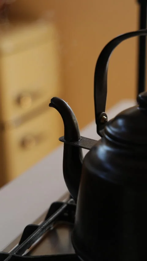 Vertical slow motion steam over a black kettle in a cozy kitchen Japan Video stock 348159776