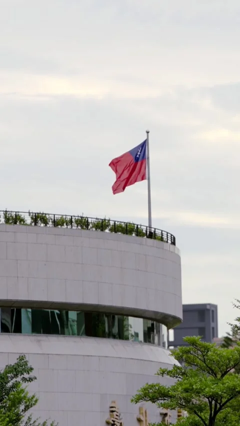 Vertical Slow motion of Taiwan flags near a modern building and greenery Stock Footage 317904852