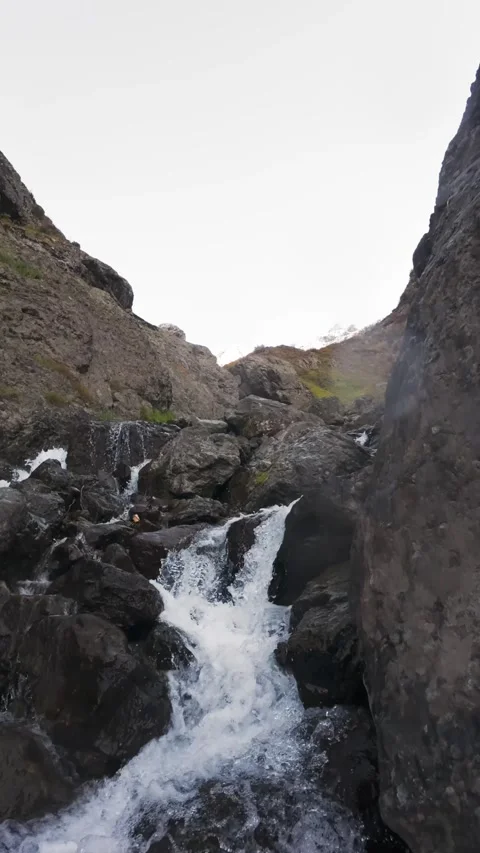 Vertical Slow Motion Tracking Shot Down a Rocky Waterfall Gorge, Vídeo Stock 330441194
