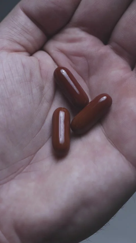 Vertical slow motion video of dark red capsules poured into palm Stock Footage 342240114