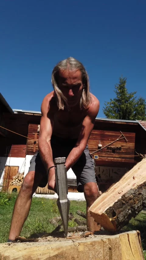 Vertical slow motion video of shirtless man chopping firewood with axe Stock Footage 345587762